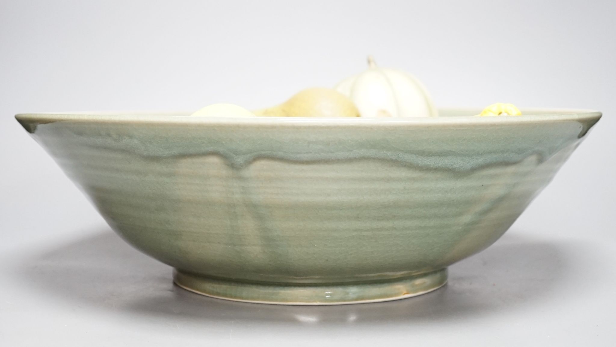 A collection of vintage Penkridge ceramic fruit including a pomegranate, melon, two bananas, limes, lemon, pear etc (18 items) in a green ceramic bowl, 42cm diameter